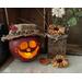 A fall table display with a handmade apple decoration lit with a candle.It is a real gourd with a happy face carved into it. 